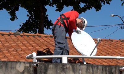 Homem instalando parabólica digital no telhado de uma residência