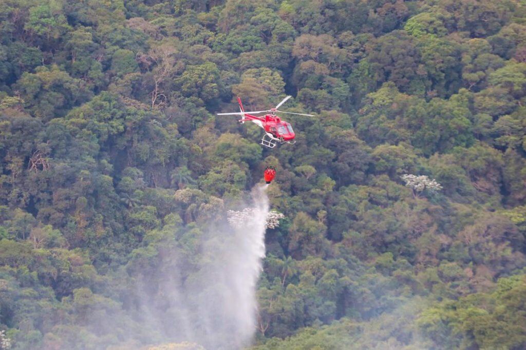 Foto exibe helcóptero apagando incêndio florestal