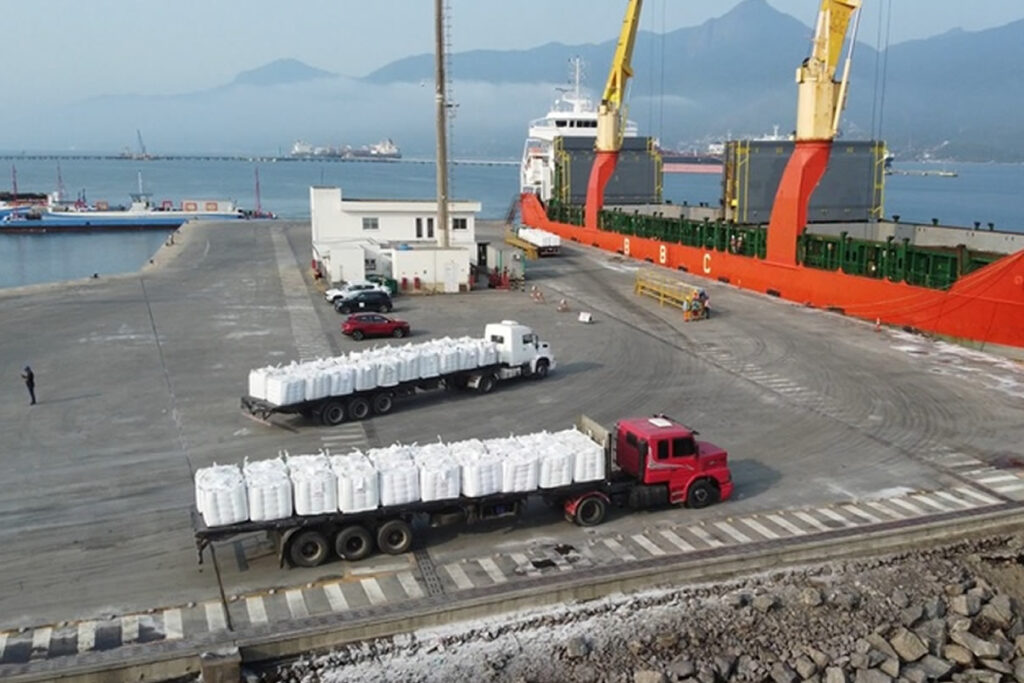 Foto exibe caminhões e navio no Porto de São Sebastião