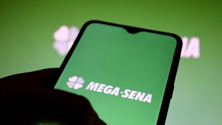 Mãos segurando celular com imagem da Mega Sena