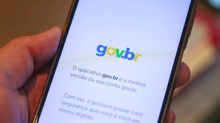 Mão segurando celular com aplicativo GOV BR aberto