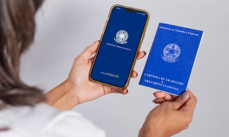 Mãos feminina segurando carteira de trabalho e celular com carteira de trabalho digital