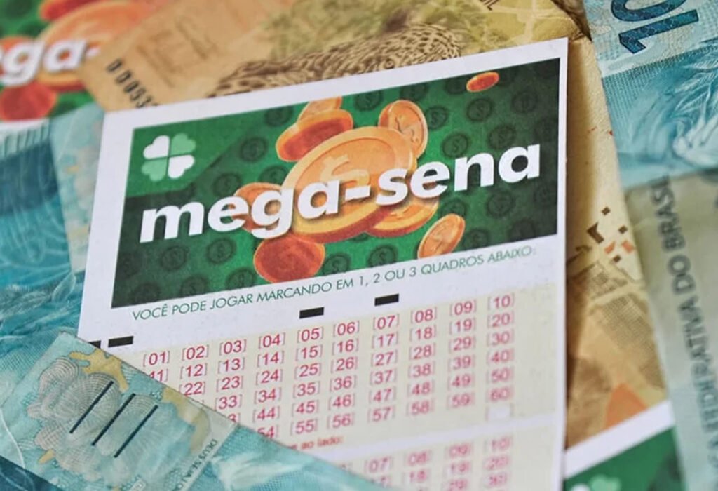 Bilhete da Mega-Sena e notas de reais ao fundo