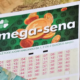 Bilhete Mega-Sena ao fundo notas de reais