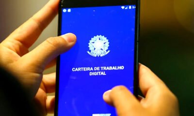 Maos segurando celular na carteira de trabalho digital brasileira