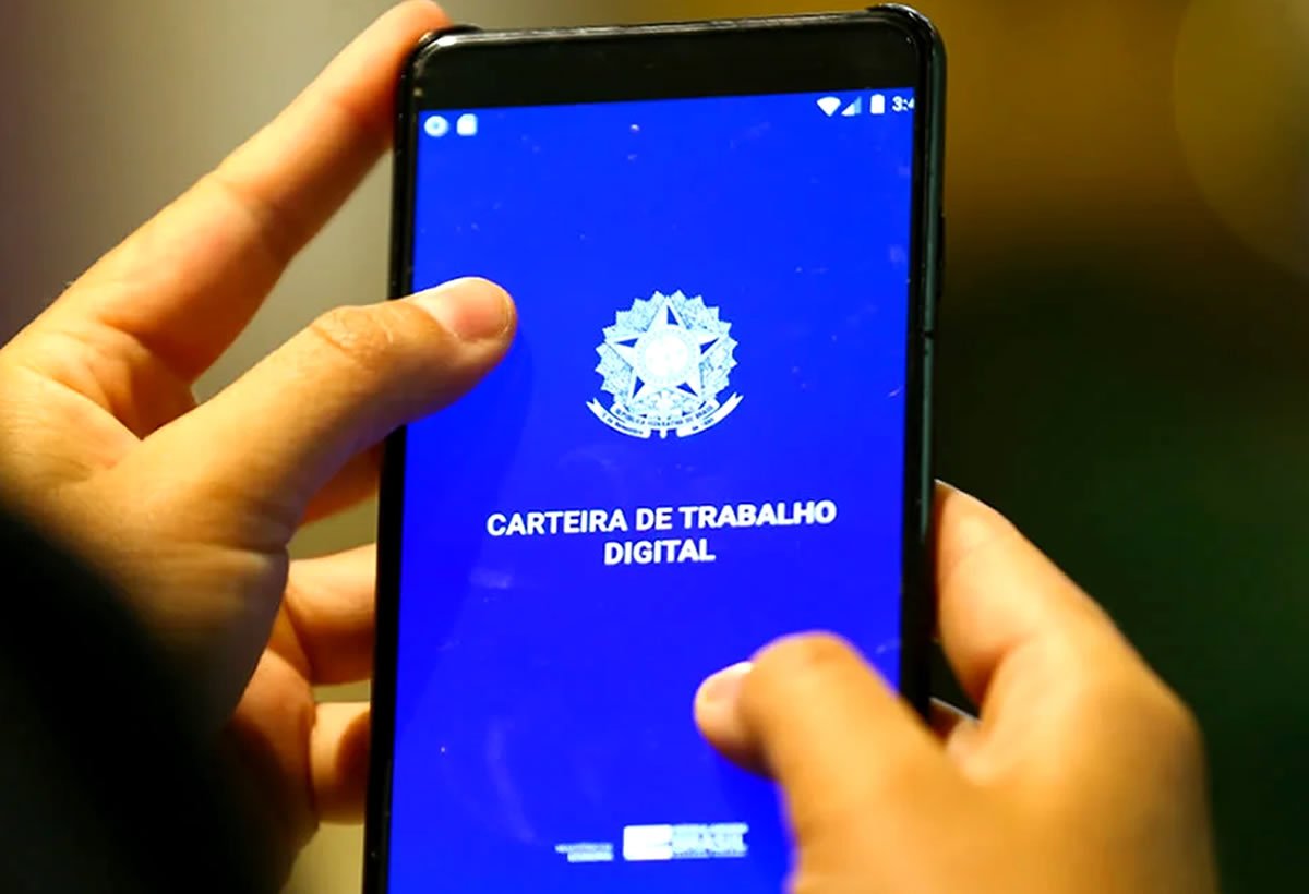 Maos segurando celular na carteira de trabalho digital brasileira